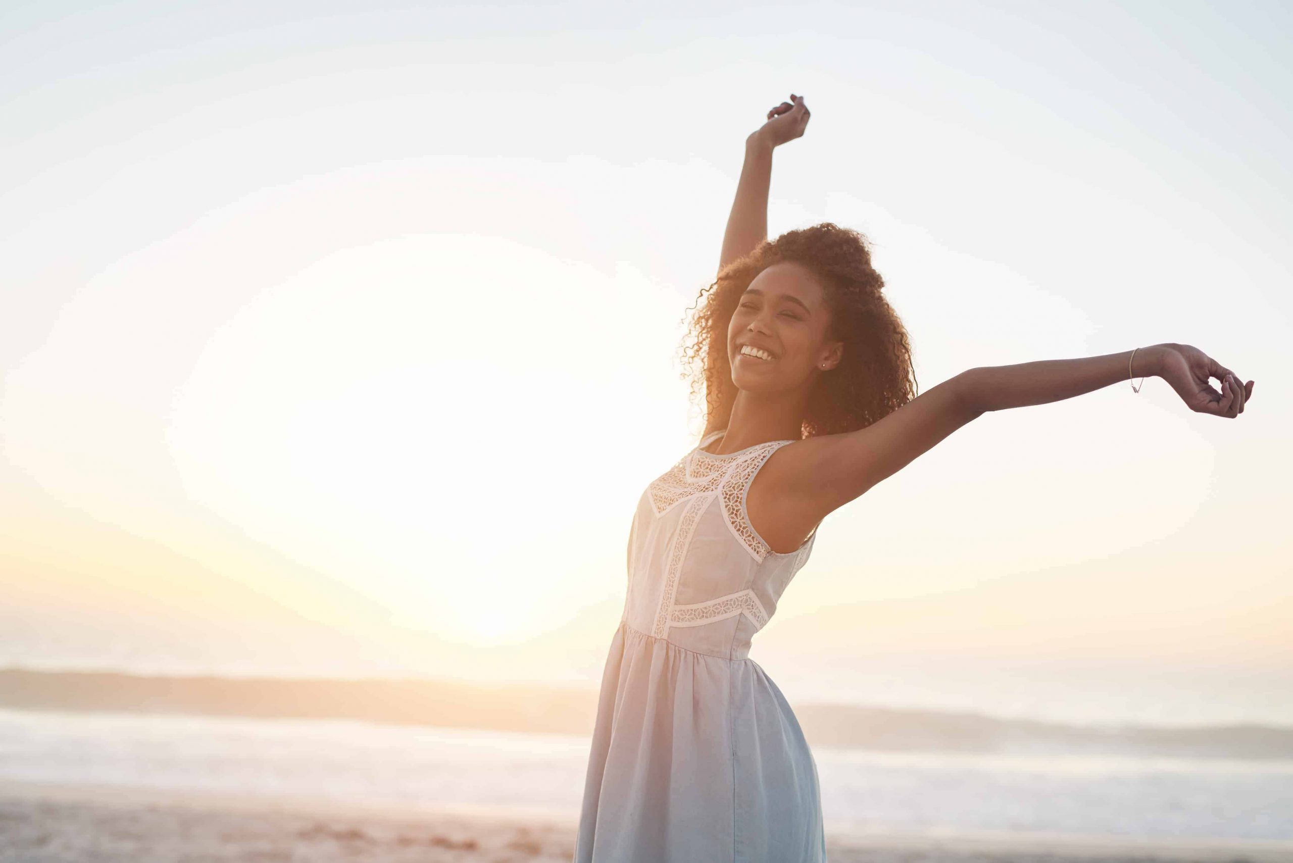Mulher feliz com os braços para cima na praia