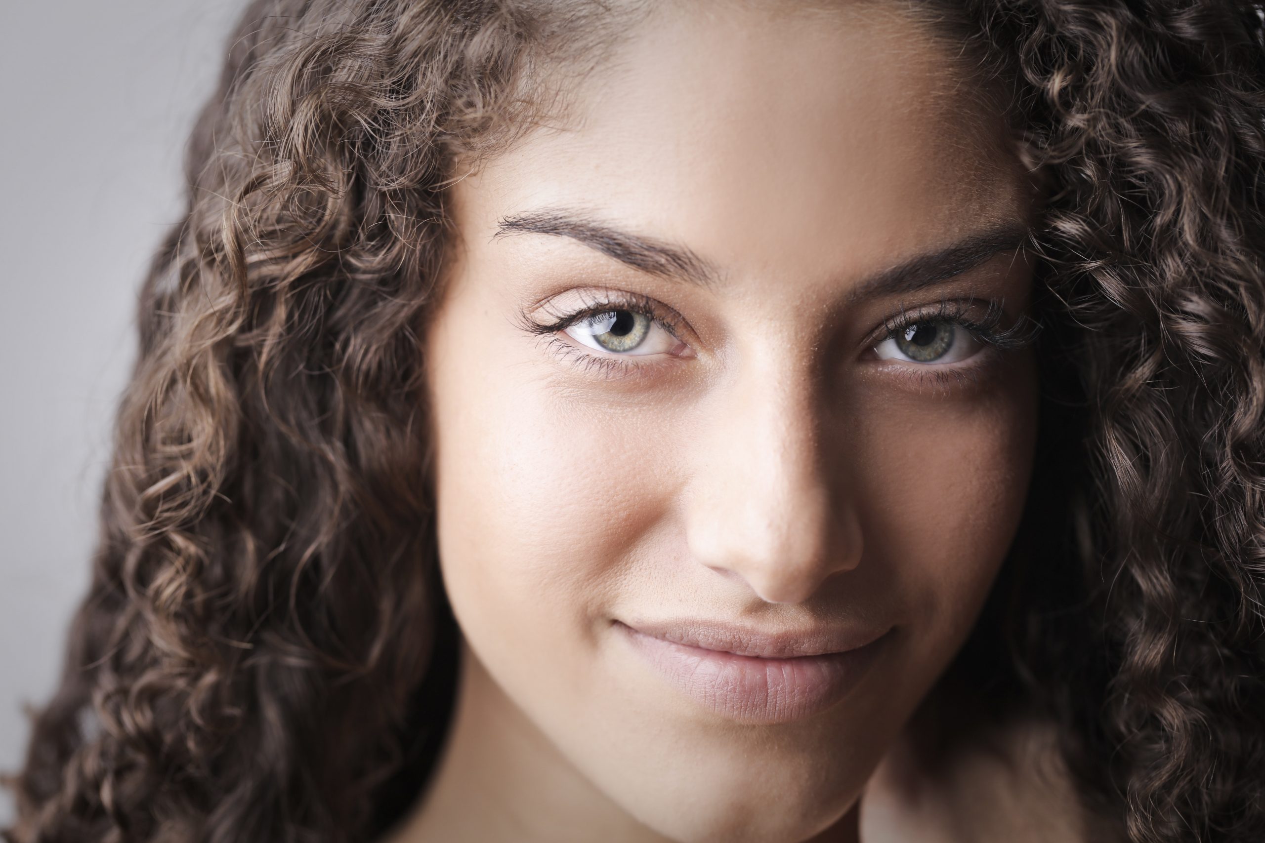 Close em uma jovem mulher com olhos verdes||Mulher feliz com os braços para cima na praia||Lente de contato BioSoft Colorida||||